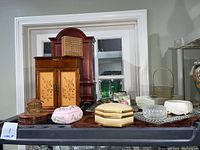 Full view of lot showing two large wooden jewelry boxes with curved tops, several small decorative boxes, two perfume trays, and a small basket arranged on a shelf