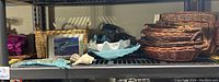 Shelf with multiple woven baskets stacked, framed picture, and clam shell-shaped dish with other assorted small items