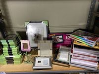 Overall view of assorted used and unopened picture frames on shelf including a digital frame box and memorial frame