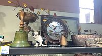 Shelf display showing various home decor items including Titanic bell, Boston Terrier doorstop, metal planter, and lighting branches