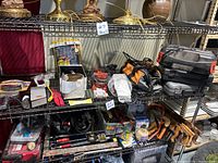 Shelves with assorted tools and hardware including power tools, hand tools, nails, brackets, and packaging boxes.