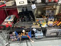 Assorted hand tools, power tools, small toolboxes, screws, and various hardware arranged on metal shelving units in a storage area.