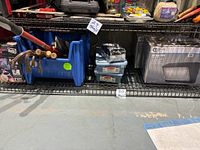 Overview showing shelves with assorted tools including crowbars, hammer, blue plastic bin with handles, and LED wall pack lights in boxes.