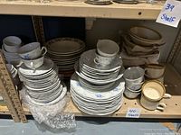 Photo of shelves with stacked dinnerware plates, cups, and bowls with floral blue and white patterns and earth-toned stoneware.