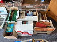 Seven cardboard boxes filled with books, some cookbooks visible, arranged on floor near a fireplace.
