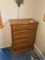 Front view of the wooden dresser with four drawers and metal handles, showing its design and finish.