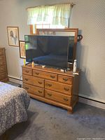 Front view of Heywood-Wakefield wooden dresser with an attached rectangular mirror and 7 drawers. TV and various items placed on top for scale and context.