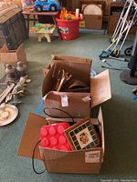 Three open cardboard boxes with various kitchen items including wooden utensils, silicone bake molds, and decorative tiles.