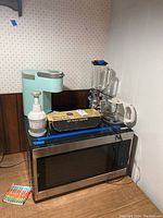 Set of kitchen appliances including LG microwave, Keurig coffee maker, blender, vegetable slicer, and slicing utensil boxed labeled 'Light - Powerful - Easy to Use'.