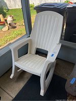 White plastic outdoor rocking chair viewed front angle showing ribbed backrest and seat, armrests, and rocker base.