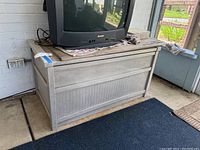 Front view of the beige outdoor plastic storage chest with a flat lid and paneled design; shows weathering and dirt.