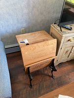 Photo showing the vintage wooden school desk from the front angle, highlighting the wood grain and iron legs.