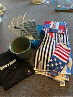 Photo showing towels, t-shirts, plastic trash can, and wire baskets laid out on carpet.