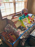 Overview of vintage toys on floral tablecloth with boxes underneath and window light