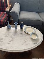 Five Wedgwood pieces laid out on marble table including plate, bowl, and three small vases