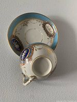 Top view of teacup on matching saucer showing blue and gold ornate design.