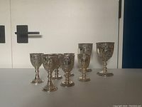 Photo showing six small ornate goblets and two larger ornate goblets arranged in a row highlighting their relative sizes and detailed designs.