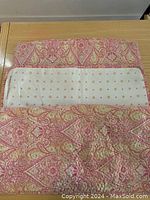 Close-up of a 26x26 inch pink paisley quilted sham folded to show white backing with small pink flowers