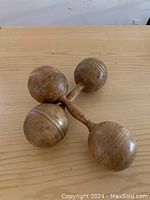 Side view of one wooden dumbbell showing spherical weights and turned handle with carved detail