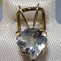 Close-up front view of heart-shaped aquamarine pendant in yellow gold setting, showing gemstone clarity and gold prongs.
