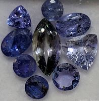 Close-up of the nine loose tanzanite gemstones showing different shapes and natural inclusions under light