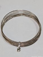 Top view of silver multi-strand bangle bracelet with heart charm.