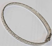 Silver bracelet in full view highlighting the flat twisted link design and diamond pattern.