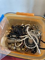 Plastic container holding mixed necklaces and bracelets