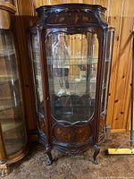 Front full view of carved wood china cabinet with curved glass panels