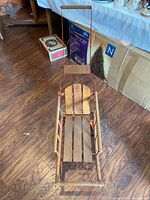 Top-down view of wooden and red metal sleigh on wooden floor.