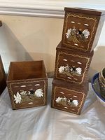 Four stacked wooden canisters with removable lids, each decorated with hand-painted white flowers, leaves, and wavy yellow borders on a brown wood background.