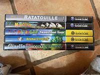 Photo showing the spines of five Nintendo GameCube game cases stacked horizontally. Titles visible: Ratatouille, Madagascar, Mario Golf: Toadstool Tour, Animal Crossing, Charlie and the Chocolate Factory.