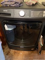 Front view of black Maytag front load washer showing the door, control panel and cycle selector dial