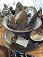 Photo showing multiple silver platters stacked vertically inside a large silver bowl, along with a small silver cup in front and a sign that says 'Silver Lot 81'