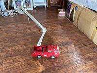 Side view of the vintage Tonka toy truck showing the extended white crane arm and red painted metal body.
