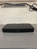 Front view of the Bose speaker showing the Bose logo and grille with a power strip in the background.