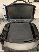 View of the Gaems portable gaming monitor in an open black plastic carrying case showing the built-in screen and foam insert inside the case.