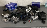 Overall view of lot showing multiple cameras, camcorders, boxes and cases