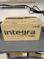 Closed original cardboard box of Integra DTR-40.1(B) AV Receiver with visible labeling and moderate wear.