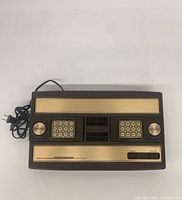 Full top view of the Mattel Intellivision console showing attached controllers and front panel with switch and branding.