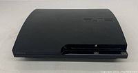 Front angle view of Sony PlayStation 3 Slim console showing matte black surface and disc slot