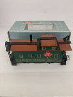 Top-down angled photo showing full length of green and brown REA train car with box in background.