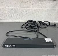 Front view of Tripp-Lite power surge protector showing the front panel with logo and power cord attached.