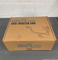 Front view of Varidesk dual monitor arm box with product illustration and branding.