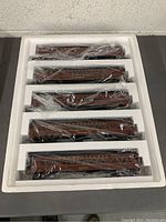 Top-down photo showing the five brown Pennsylvania train cars inside white styrofoam packaging, cars wrapped in plastic.