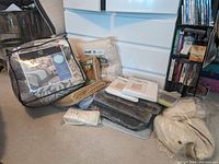 View of multiple bathroom rugs, comforter set in packaging, grippies, and other bedding items arranged on floor.