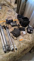 Sony Mavica digital camera, Vivitar 300Z zoom camera, Polaroid 600 film camera, tripods, cases shown on bed