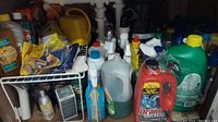 Shelf with assorted cleaning supplies including Drano Ultra, spray bottle, Mr. Clean, and liquid potpourri
