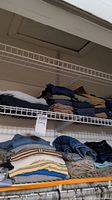 Folded men's shirts and pants stacked on wire shelving