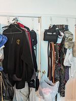 View of hanging men's jackets, fleece pullovers, belts, ties, and pants on door hooks and hangers